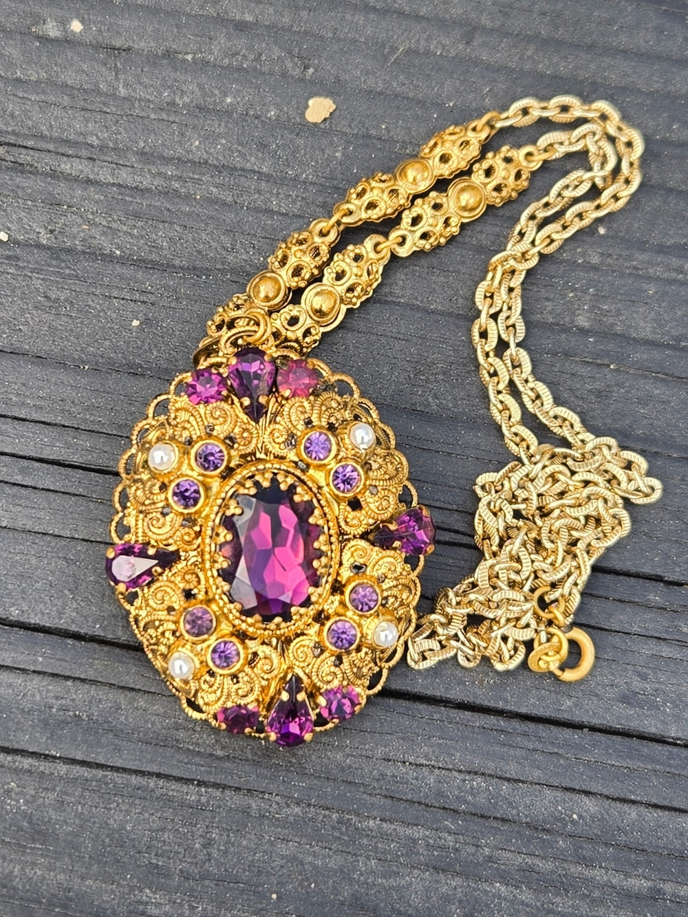 Vtg. gold toned filigree and purple rhinestones faux pearl w/chain necklace.
